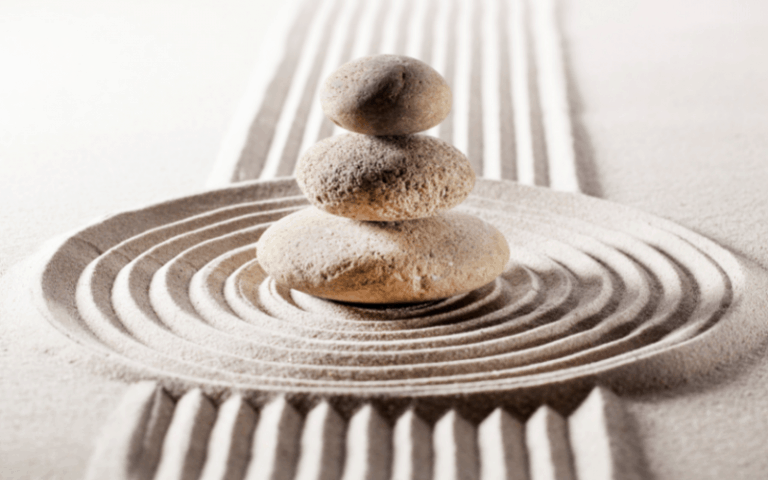 Three rocks on the sand, stacked on top of each other, to demonstrate Energetic Balance Enhancement